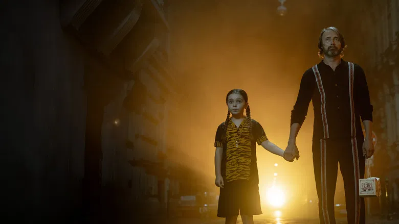 Mads Mikkelsen as the hitman neighbor holding a weapon in a dimly lit hallway